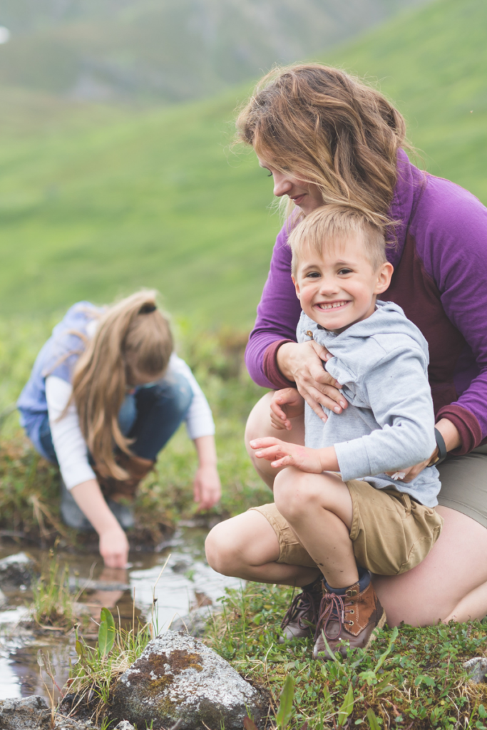 mom and kids playing near a stream