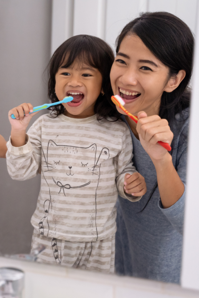 mom and daughter brushing their teeth in the bathroom