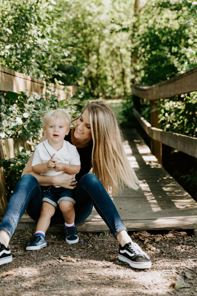 mom and son sitting on the end of a bridge in the woods - embracing change