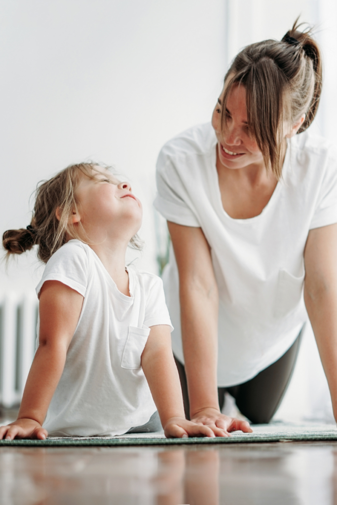 mom and daughter wearing white t-shirts doing a yoga pose on the floor