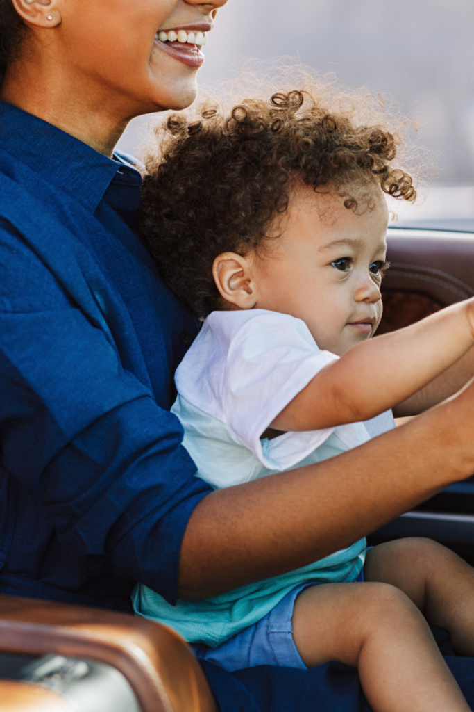 A mom holding a baby while driving