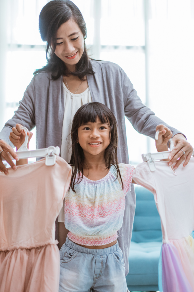 A mom and daughter holding up two dresses to choose from