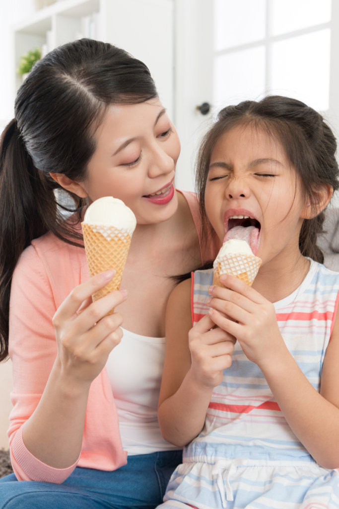 mom and daughter eating ice cream cones in the living room of a house 