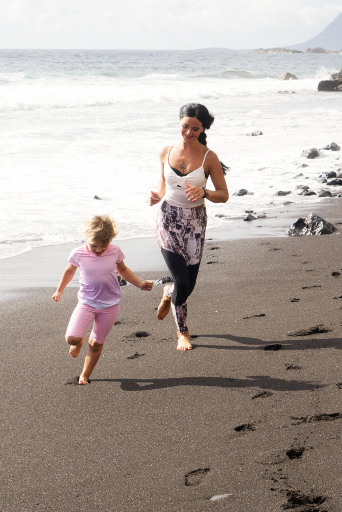 mom and daughter running on the beach in the summer having fun