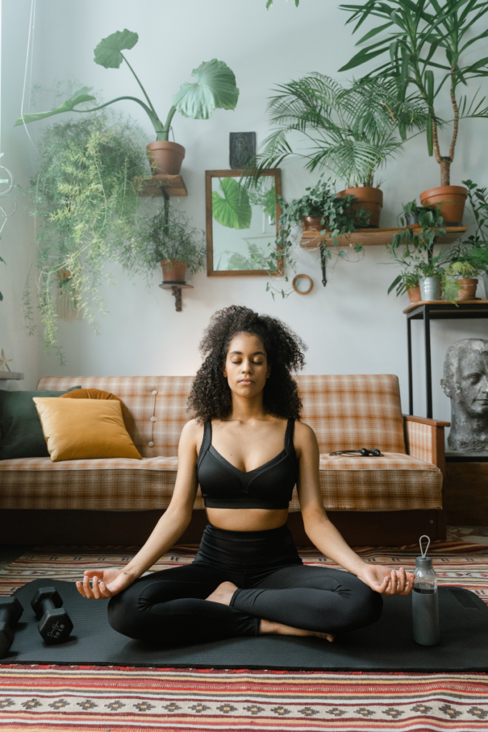 woman sitting on the floor meditating wearing a black sports bra and black yoga pants