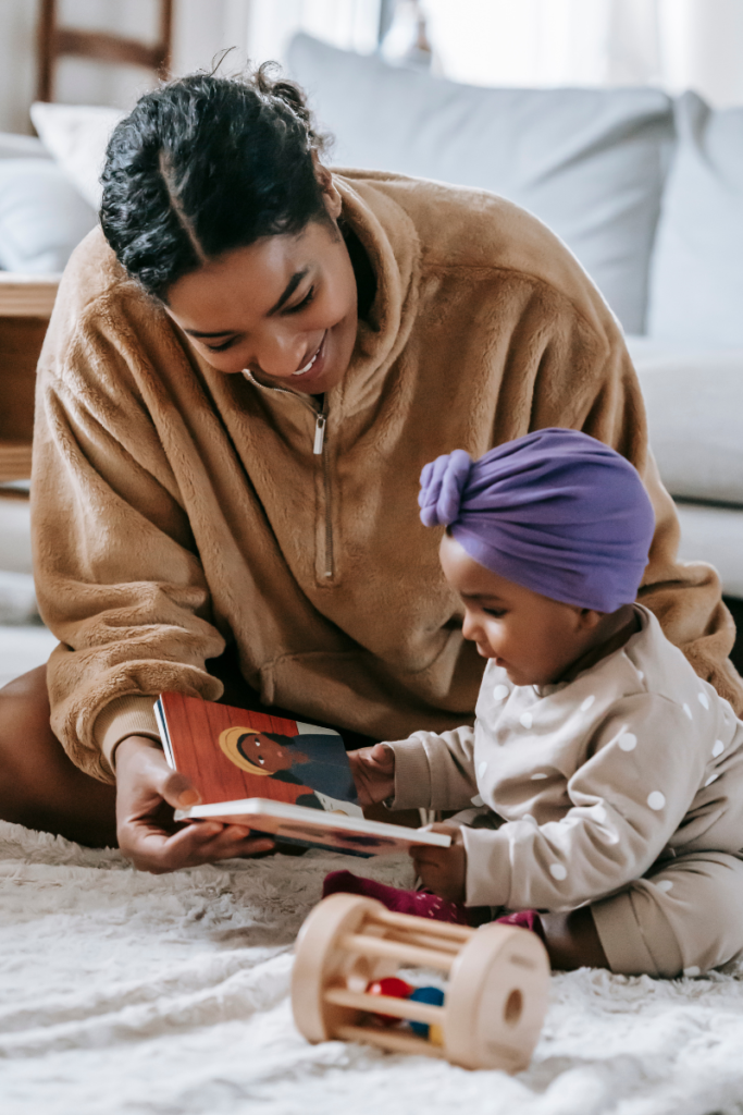 mom and baby playing with a hard book on the floor